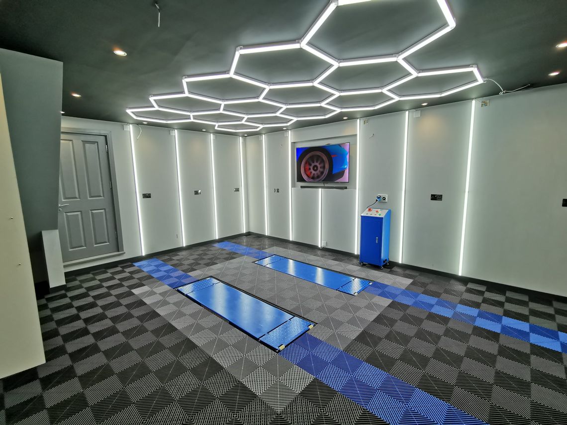 A home garage with Swisstrax ribtrax flooring. There are hexagonal lights in the ceiling