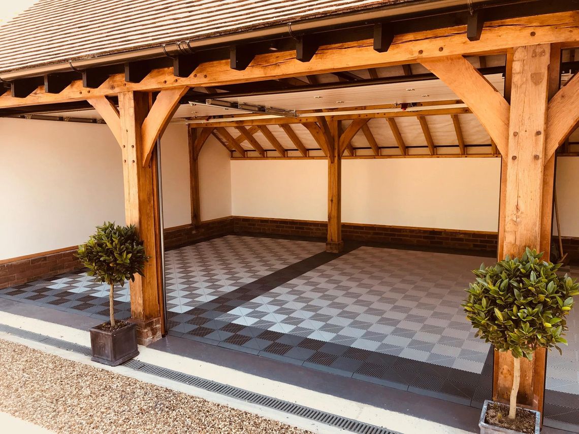 An open wooden framed garage with grey swisstrax flooring on the ground.