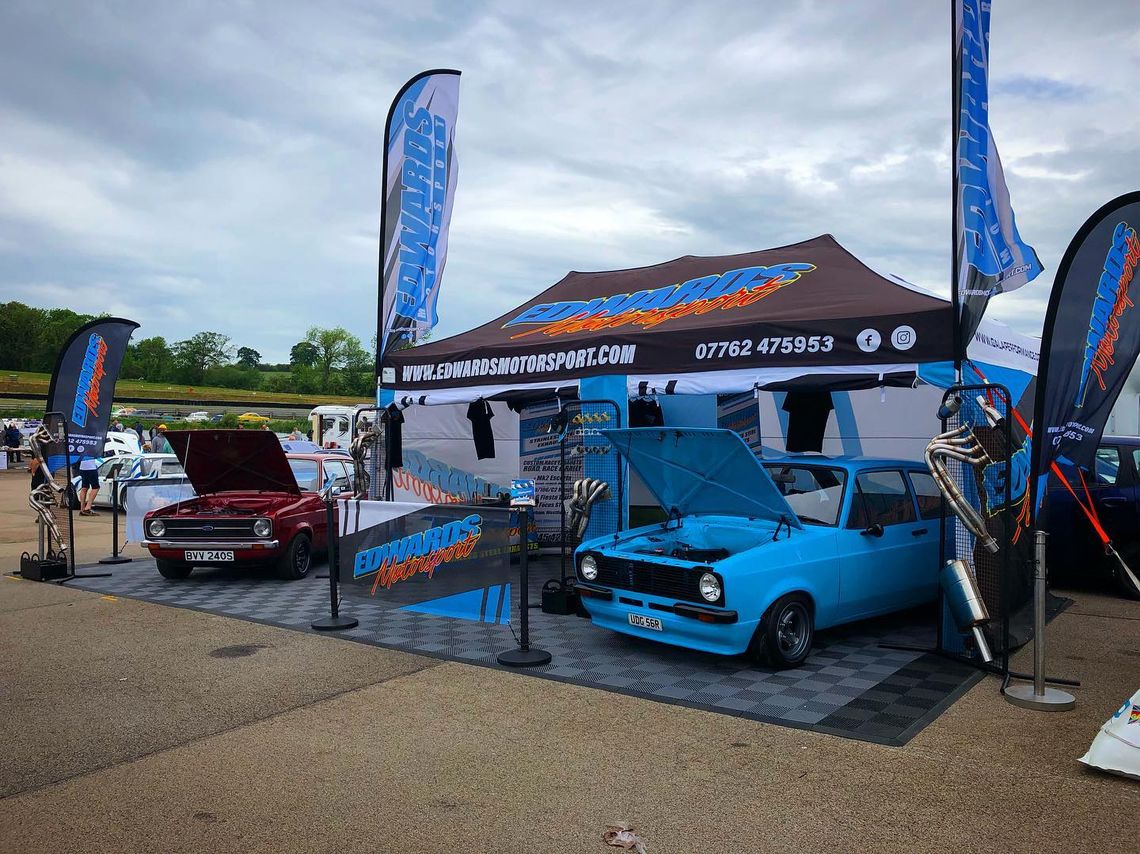 A blue car beneath a printed motorsport tent