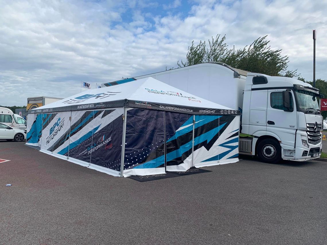 A blue and white motorsport awning by a truck