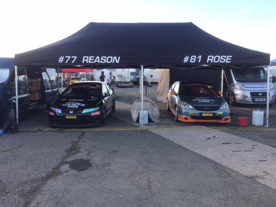 A large pop up race tent with 2 cars beneath it