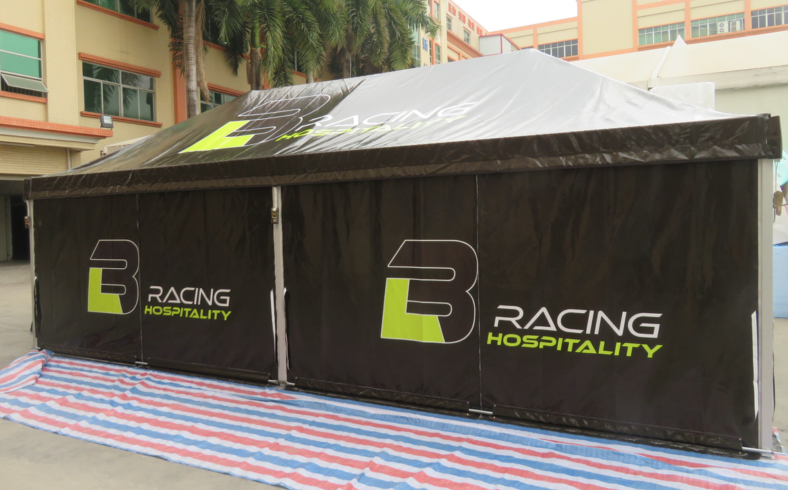 A black motorsport tent printed with yellow branding